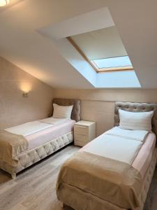 two beds in a room with a skylight at Villa Moste Ljubljana - Modern apartments with Pool, EV station & free parking in Ljubljana +134 photos