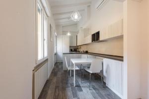a kitchen with white cabinets and a table and chairs at Vettori Hideaway by MMega in Florence