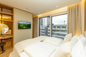 a bedroom with a white bed and a large window at Kö102 Prime Suites in Düsseldorf