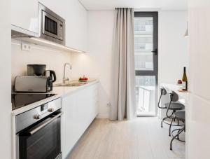 a white kitchen with a sink and a table at LSA Parque by Numa in Lisbon
