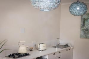 a kitchen with white appliances and two hanging lights at Clivedon Cottage in Sunland +60 photos