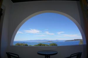 an arched window with a view of the water at Villa Elizabeth Apartments in Ouranoupoli