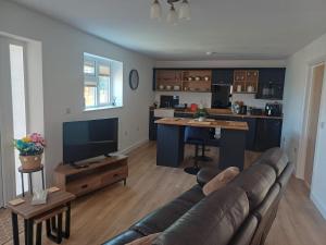 a living room with a couch and a kitchen at Ives End in Buxton