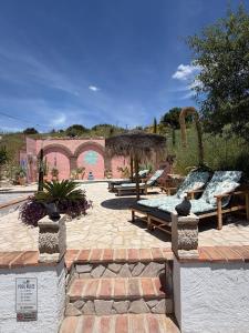 a patio with benches and a building with arches at Casita Malacitano, Caminito del Rey in Valle de Abdalagís