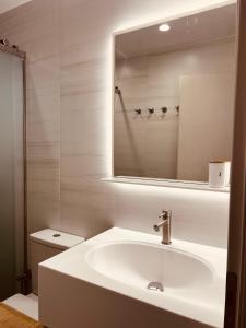 a white bathroom with a sink and a mirror at Alkisti's seaside apartments in Pythagoreio