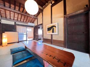 a dining room with a wooden table and blue cushions at 瀬戸内海を望む庭付き古民家サウナ宿 一棟貸切 in Takamatsu