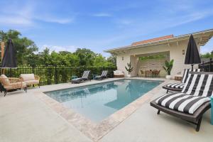 a swimming pool with chaise lounges and chairs on a patio at Spacious 3BR - Pool - Beach Nearby in Pass Christian