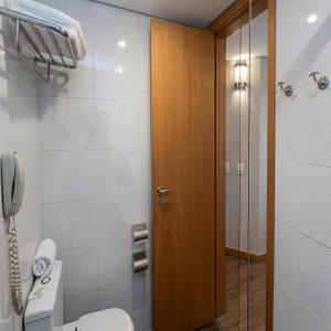 a bathroom with a toilet and a wooden door at 1309 - Hotel & Residence Sol Alphaville Flat in Barueri +2 photos