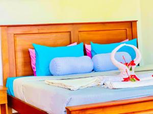 a bed with blue pillows and two swans on it at Ceylan Crest in Ella