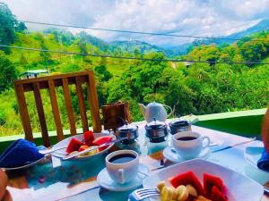 a table with plates of food and cups of coffee at Ceylan Crest in Ella