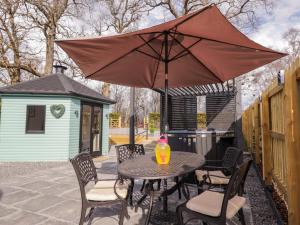 a table and chairs with an umbrella on a patio at Little Oaks in Dingwall