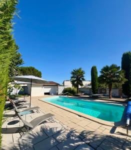 a swimming pool with lounge chairs and an umbrella at La Marelle in Corberon