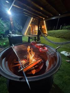 a grill with meat on it in a yard at night at Sítio das Amoreiras- Cabana in Tabapira