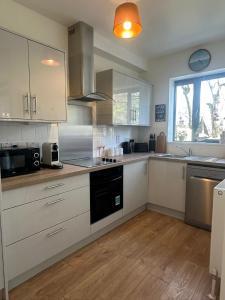a kitchen with white cabinets and a stove top oven at House Sleeps 6 with Parking in Coad