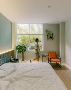 a woman is standing in a bedroom looking out the window at Mik Stay in Danang