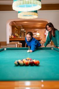 a woman and a young boy playing pool at Hotel Miramonti Corvara in Corvara in Badia