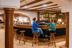 a man and two women sitting at a bar at Hotel Miramonti Corvara in Corvara in Badia