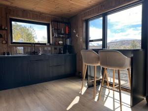 a kitchen with two bar stools and two windows at Stryn Nature Lodge in Stryn