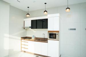 a kitchen with white cabinets and a sink at Horizon Stay Nizwa in Firq