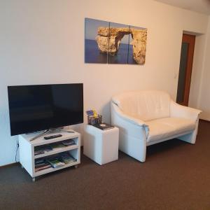 a living room with a flat screen tv and a chair at BnB im Grossacker in Münchwilen