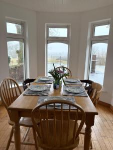 a dining room with a wooden table with chairs and windows at Ashmore Mews in Galway