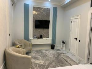 a bedroom with two chairs and a television on a wall at Shahzam Hotel in Samarkand