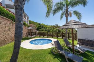 a backyard with a swimming pool and two chairs and an umbrella at Alcaidesa Golf in La Alcaidesa