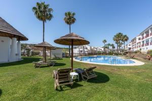a pool with chairs and umbrellas in a yard at Alcaidesa Golf in La Alcaidesa