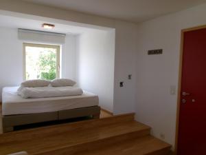 a white room with a bed with a window at huisje Kraaiberg in Heuvelland