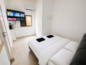 a white bedroom with a bed and a flat screen tv at בית פרטי ליד הכנרת בקריית שמואל מושלם לאירוח בשבתות ובחגים in Tiberias