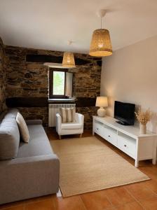 a living room with a couch and a tv at RURAL PRADO in San Tirso de Abres