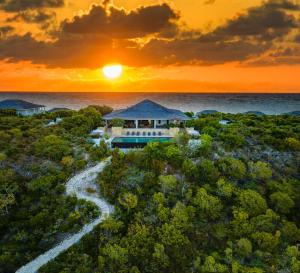 a house in the forest with the sunset in the background at Sailrock South Caicos, Small Luxury Hotels of the World in South Caicos
