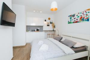 a white bedroom with a bed and a tv at Narancin Apartments in Trogir
