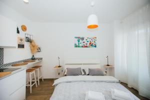a white bedroom with a bed and a kitchen at Narancin Apartments in Trogir