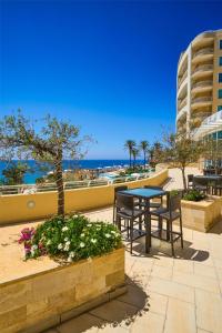 a patio with a table and chairs and the beach at Radisson Blu Resort & Spa, Malta Golden Sands in Mellieħa