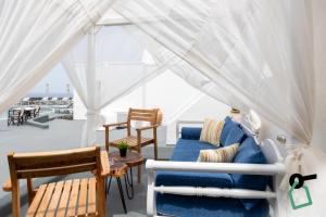 a living room with a blue couch under a white tent at Hotiday Santorini Seafront in Santorini