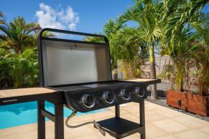 a barbecue grill sitting next to a pool at Villa Ti'Palm in Saint-François