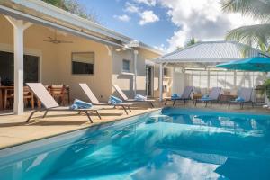 a swimming pool with chairs and a house at Villa Ti'Palm in Saint-François +31 photos