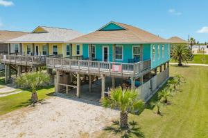 an aerial view of a blue house with palm trees at Steps from the Jetty & Beach in Surfside Beach
