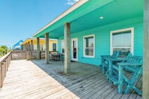 a blue house with chairs on a wooden deck at Steps from the Jetty & Beach in Surfside Beach