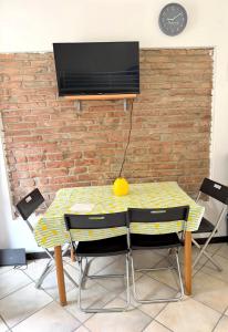 a table with chairs and a television on a brick wall at Lemon House in Stezzano