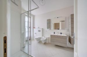 a white bathroom with a toilet and a sink at Villa dante in Alba