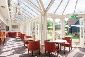a conservatory with tables and chairs and windows at Holiday Inn Ashford Central by IHG in Ashford