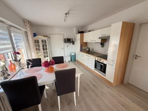 a kitchen with a table and chairs and a kitchen with white cabinets at Vakantiewoning MaRa in Neuenhaus