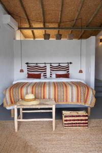 a bedroom with a large bed with a bench at Monte da Palmeira in Vila Nova da Baronia