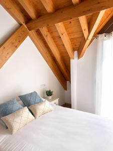 a bedroom with a white bed with wooden ceilings at Duplex El Acebuche in Arroyo Frio +23 photos