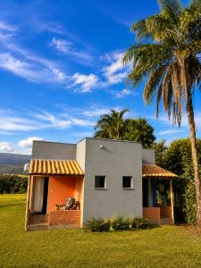a small house with a palm tree in a field at Pousada Serra do Encanto in Delfinópolis