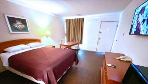 a hotel room with a bed and a desk with a phone at Thunderbird Motel Hillsboro in Hillsboro