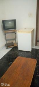 a living room with a tv and a table at Chambre d'hôtes à louer in Pikine