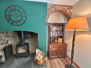 a living room with a fireplace and a clock on the wall at Herberts Cottage in Wormegay
